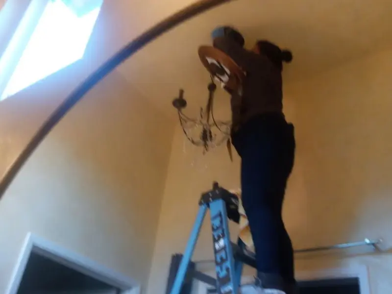 Electrician installing a chandelier in a Hawthorne residence